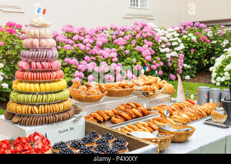 Variante von Süßgebäck, Gebäckfrucht-Schalen mit blauen Beeren, Erdbeeren, Himbeeren, Schachtel mit Makropyramide, Korb mit Croissants, gla Stockfoto