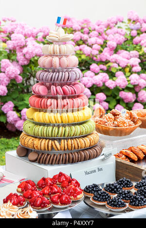 Variante von Süßgebäck, Gebäckobstschalen mit blauen Beeren, Erdbeeren, Himbeeren, Schachtel mit Macronenpyramide, Korb mit Croissants, gla Stockfoto