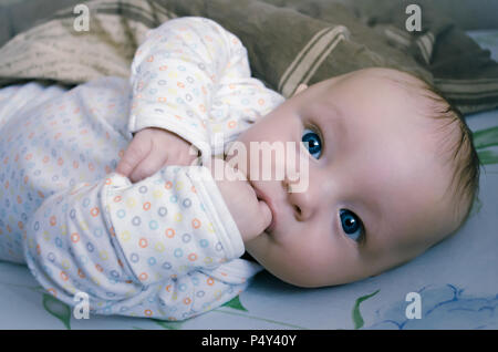 Baby drei Monate alt mit großen blauen Augen Saugen an seinem Finger Stockfoto