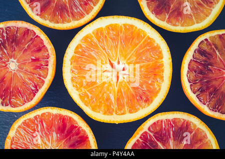 In Scheiben geschnitten Blutorangen Textur. Citrus Hintergrund. Schneiden reif saftig sizilianischer Blutorangen Früchte auf der Rückseite Hintergrund. Ansicht von oben. Stockfoto