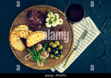 Italienische Antipasti Wein Snacks. Mozzarella, mediterrane Oliven, Prosciutto di Parma, Bresaola, getrocknete Tomaten und Toast auf hölzernen Boa Stockfoto