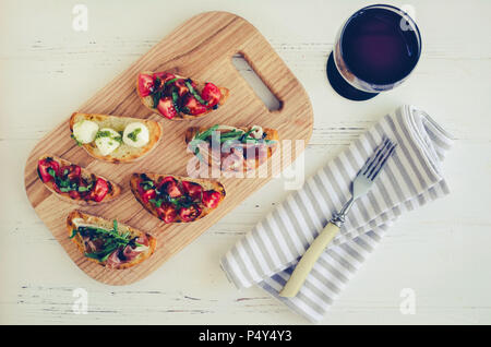 Brushetta für Wein. Vielzahl von kleinen Sandwiches mit Glas Rotwein serviert. Leckerer Snack, Vorspeise, auf Party oder Picknick zeit Antipasti. Ital Stockfoto