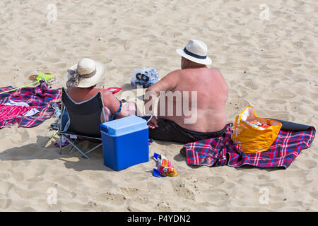 Bournemouth, Dorset, Großbritannien. 23. Juni 2018. UK Wetter: überfüllte Strände an einem schönen sonnigen Tag als Besucher gehen zum Meer den Sonnenschein zu machen, da die Temperaturen für die Hitzewelle steigen. Paar Sonnenbaden am Strand - Übergewicht Fat Man Stockfoto