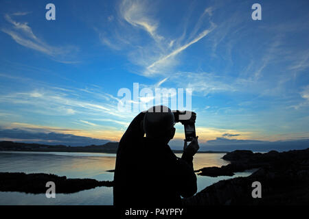Isle of Mull, Großbritannien. 23. Juni 2018. Mann ein Foto mit seinem Telefon der wunderbaren Himmel über der Isle of Iona in der Inneren Hebriden in Schottland. Der klare Himmel werden der Beginn der großen Wettervorhersage für die kommende Woche Credit: PictureScotland/Alamy leben Nachrichten Stockfoto