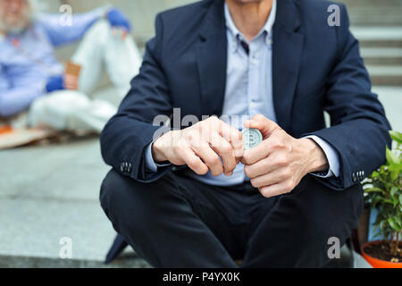 Office Manager tragen dunkler Anzug holding Münze in Händen Stockfoto
