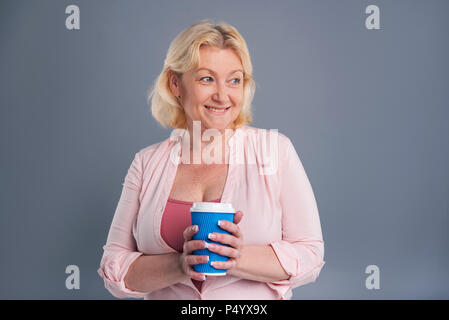 Fröhliche Frau mittleren Alters, die blaue Kaffeetasse Stockfoto