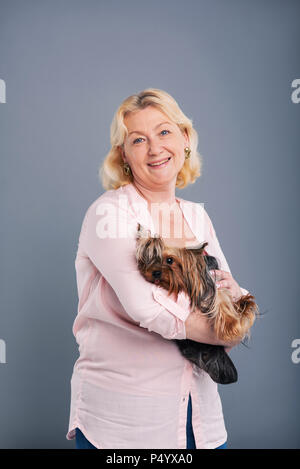 Gerne Frau mittleren Alters mit ihrem Hund posing Stockfoto