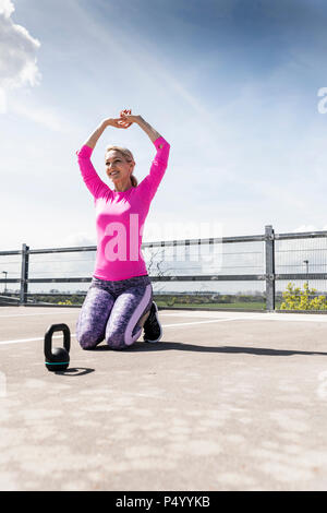 Frau Training mit Hanteln, kniend auf dem Boden Stockfoto