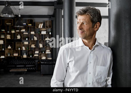 Reifer Mann im Loft lehnte sich gegen eine Spalte Stockfoto