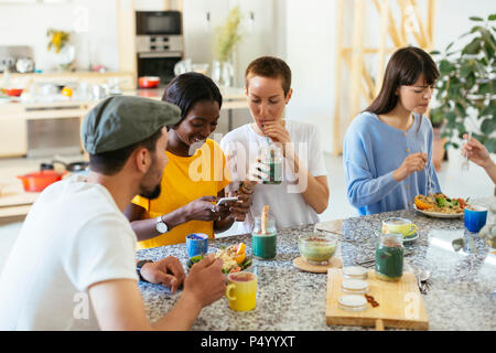 Freunde an der Arbeitsplatte in der Küche Essen und Trinken sitzen Stockfoto