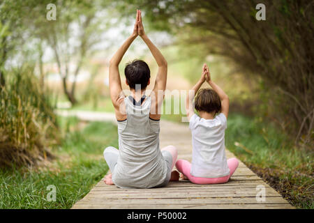 Hintere Ansicht von Mutter und Tochter Yoga am Boardwalk Stockfoto