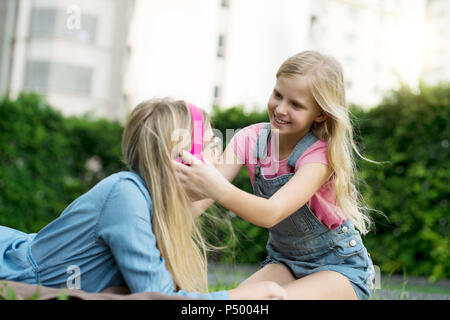 Glückliche Mutter und Tochter hören die Musik zusammen im Garten Stockfoto