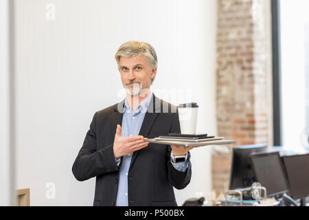 Zuversichtlich Geschäftsmann präsentiert mobile Geräte mit Tasse Kaffee auf der Oberseite Stockfoto