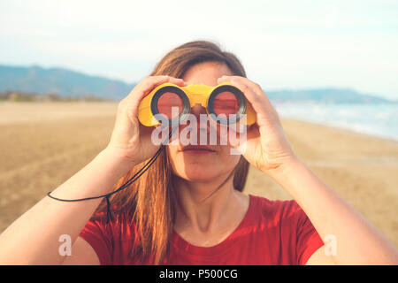 Frau mit Fernglas am Strand Stockfoto