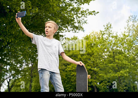 Junge mit Skateboard selfies mit Smartphone Stockfoto