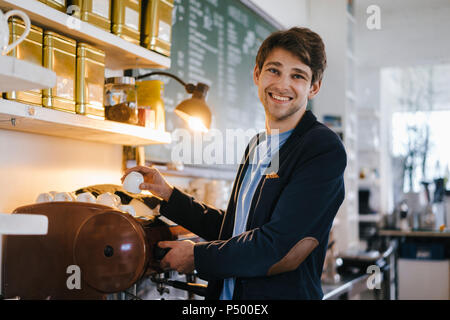 Portrait von lächelnden Mann in einem Cafe holding Schale Stockfoto