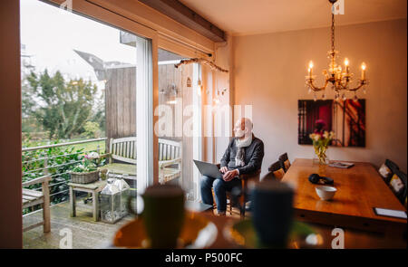 Ältere Mann zu Hause sitzen, mit laptop Stockfoto