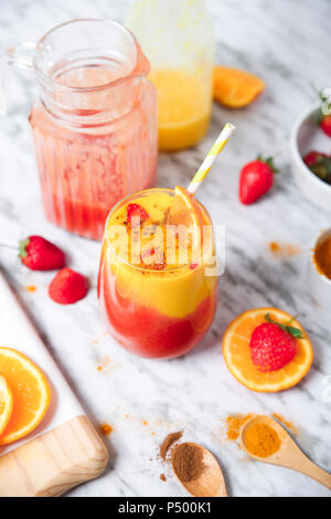 Erdbeeren und Orangen Smoothie mit Kurkuma und Zimt auf Marmor Stockfoto