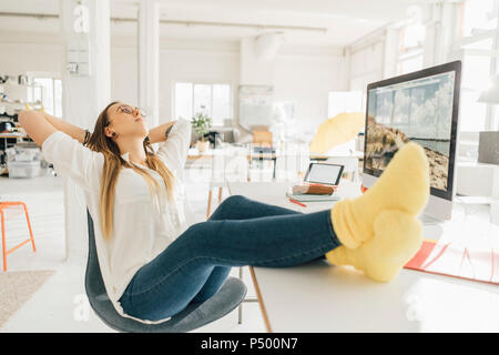 Junge Freiberufler mit Füßen bis Entspannung am Schreibtisch in einem Loft Stockfoto