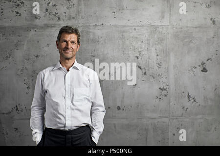 Portrait von lächelnden reifer Mann vor der Betonwand Stockfoto