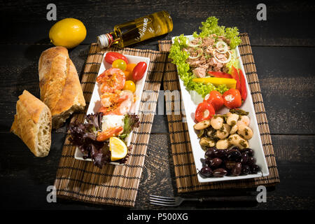 Antipasti, Thunfisch, Salat, gefüllte Paprika, weiße Bohnen, schwarze Oliven, Garnelen, saure Sahne, Tomaten und Weißbrot Stockfoto