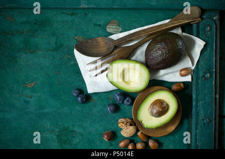 Tuch, Salat Besteck, Avocados, Blaubeeren und Muttern auf grünem Boden Stockfoto