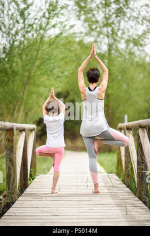 Hintere Ansicht von Mutter und Tochter Yoga am Boardwalk Stockfoto