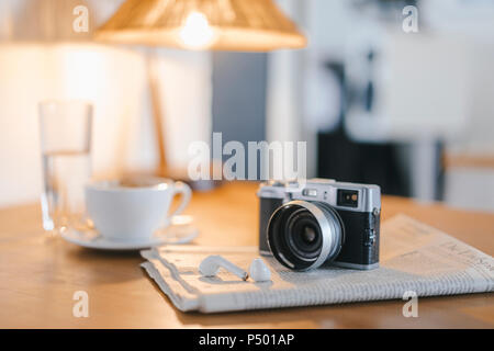Ohrhörer, Zeitung und Kamera am Tisch in einem Cafe Stockfoto