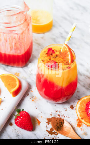 Erdbeeren und Orangen Smoothie mit Kurkuma und Zimt auf Marmor Stockfoto