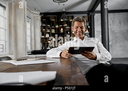 Lächelnd reifer Mann mit digitalen Tablette im Loft Büro Stockfoto