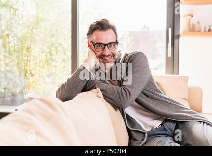 Portrait von lächelnden Mann entspannt auf der Couch zu Hause Stockfoto