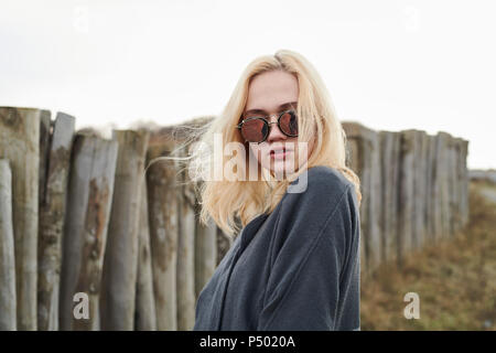 Porträt der blonde junge Frau mit verspiegelten Sonnenbrillen am Strand Stockfoto