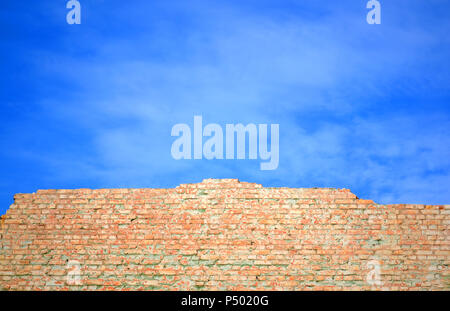 Wand aus rotem Backstein gegen den blauen Himmel erschüttert Stockfoto