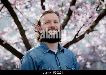 Portrait von bärtigen Mann vor der blühenden Kirschbaum Stockfoto