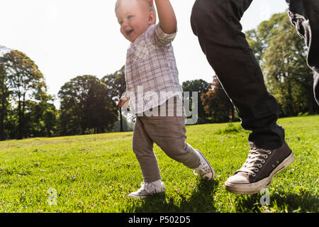 Vater gehen Hand in Hand mit dem Sohn in einem Park Stockfoto