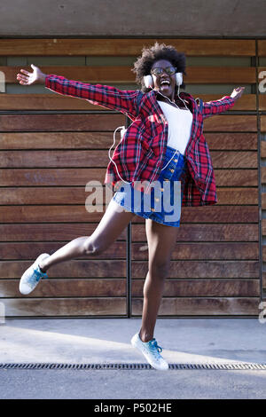 Porträt der jungen Frau gerne Musik hören mit Kopfhörern springen in die Luft, Stockfoto
