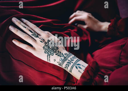 Woman's Hand mit Henna Tätowierung auf rotem Tuch Stockfoto