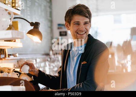 Lächelnd Mann in einem Cafe holding Schale Stockfoto