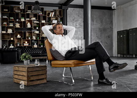 Reifer Mann sitzen auf Stuhl in der Loft entspannen Stockfoto