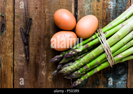 Grüner Spargel und braune Eier auf Holz Stockfoto