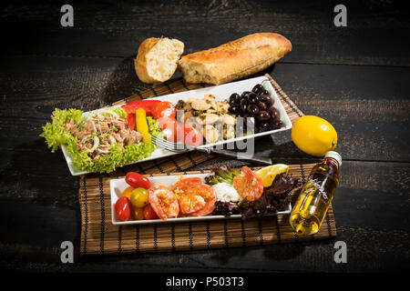 Antipasti, Thunfisch, Salat, gefüllte Paprika, weiße Bohnen, schwarze Oliven, Garnelen, saure Sahne, Tomaten und Weißbrot Stockfoto