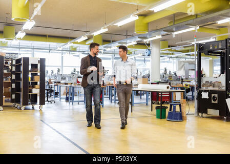 Zwei Männer laufen und sprechen in der Factory Stockfoto