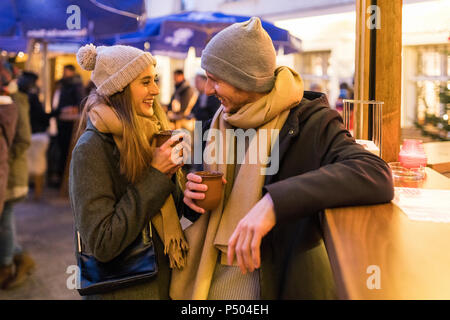 Glückliches junges Paar trinken Glühwein am Weihnachtsmarkt Stockfoto