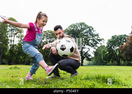 Vater Fußball spielen mit Tochter in einem Park Stockfoto