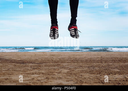 Die Beine des Menschen springen in die Luft am Strand Stockfoto