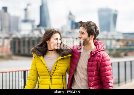 UK, London, junges Paar gehen Arm in Arm auf einer Brücke Stockfoto