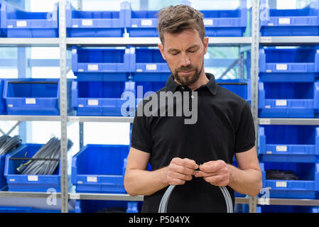 Mann hält das Kabel in der Fabrik Abstellraum Stockfoto