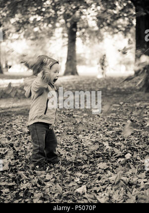 Glückliches Kind Blätter Werfen im Park Stockfoto