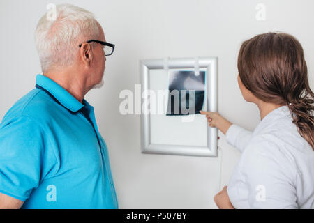 Arzt überprüfen x-ray Image mit älteren Patienten in der Arztpraxis Stockfoto
