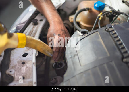 Automechaniker Wechseln von Motoröl in einem dreckigen Motor Stockfoto